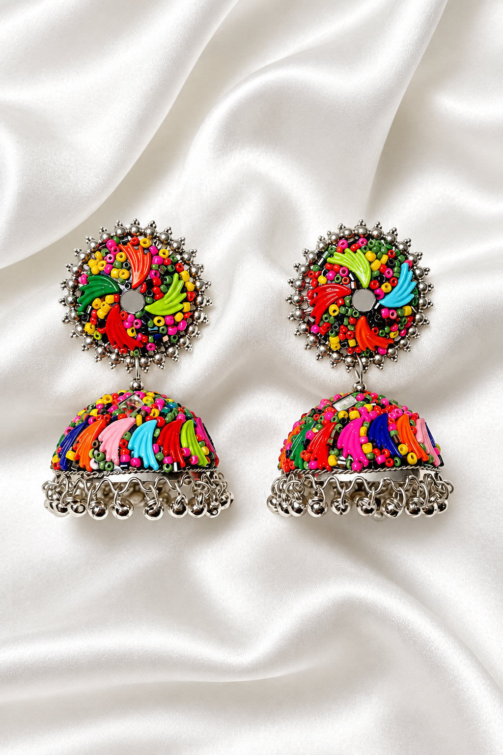 Vibrant multicolor hand‑painted fan design mirror & seed bead silver jhumka earrings on soft white silk background — ethnic bridal festive jewelry.