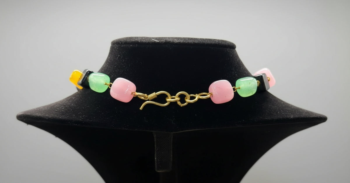 Necklace with colorful beads on a black mannequin bust against a gray background