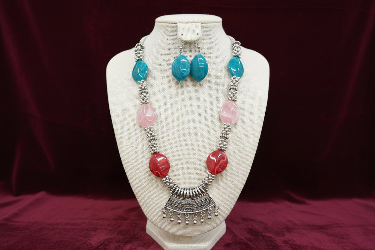 Necklace with colourful beads and silver accents on a black stand.