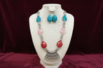 Necklace with colourful beads and silver accents on a black stand.
