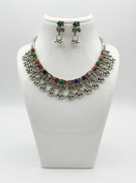 Premium silver oxidised multicolour floral choker set on a display stand, highlighting the green stone accents and high-grade artisanal craftsmanship.
