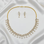 Gold-tone necklace and matching drop earrings set with clear teardrop-shaped stones, displayed on a gray jewelry presentation tray.