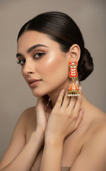 Orange colour pair of gold-platedMeenakari drop Jhumka earrings displayed on a stand, featuring intricate designs and studded with stones.