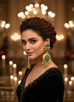 Ornate earrings with green stones and gold accents on a textured surface