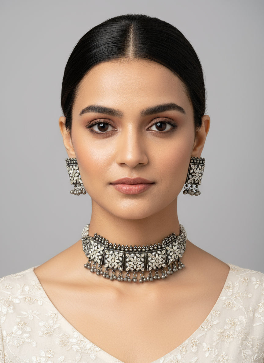 Ornate silver jewelry set on a black stand with a blurred background