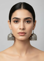Close-up of a woman wearing silver earrings against a neutral background by famaza couture