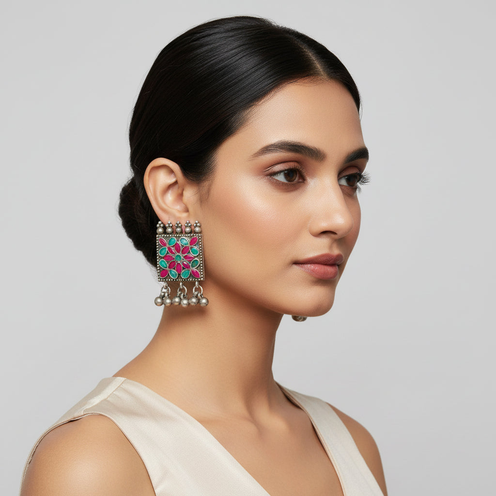 Pair of earrings with floral design and hanging beads on a white background