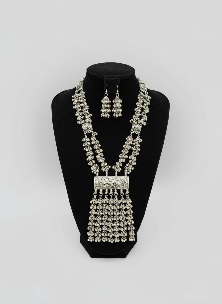 Silver necklace and earrings set on a black mannequin bust with a blurred background