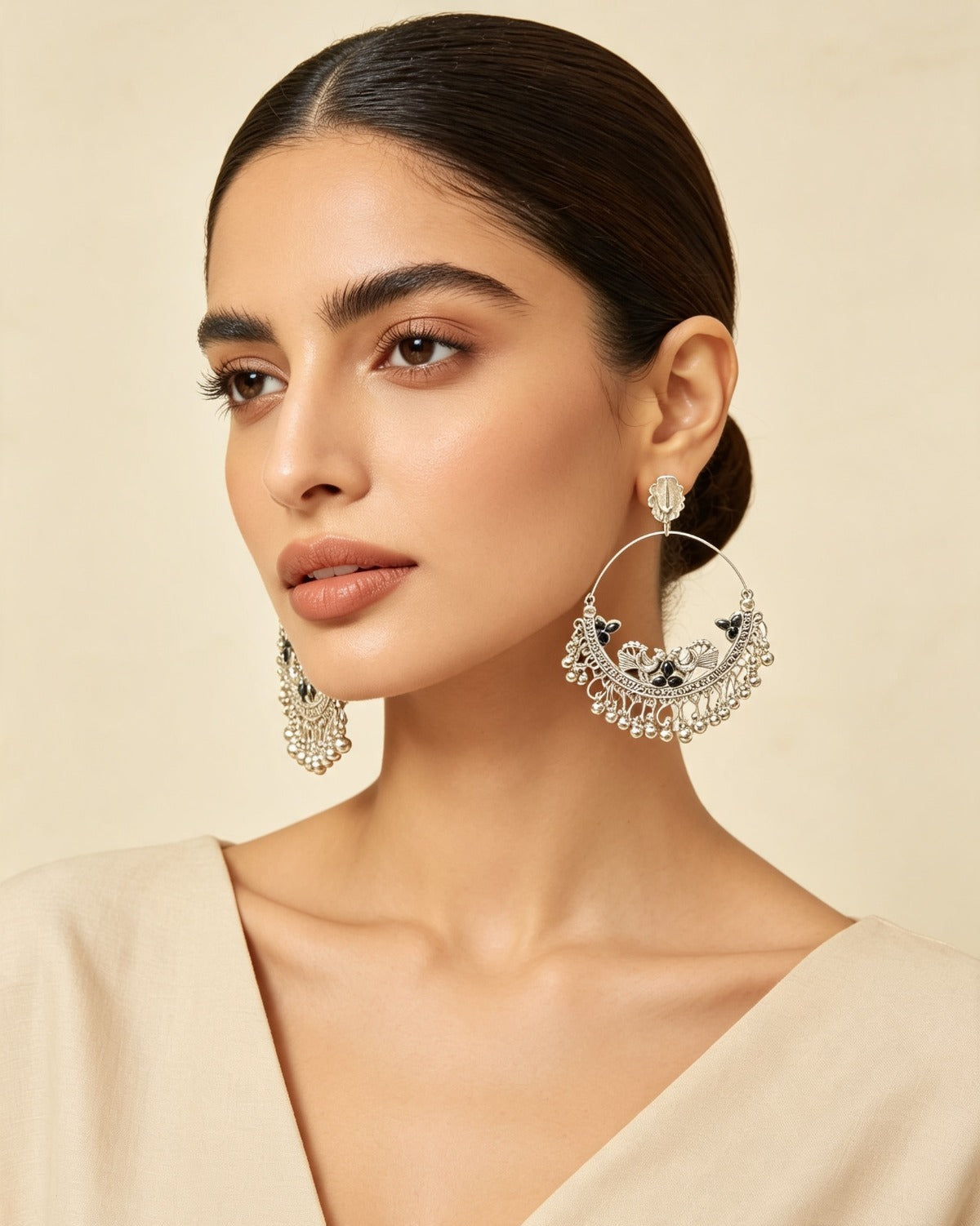Black worn on model: Model in a cream outfit wearing silver-tone peacock chandbali earrings with black accents and ghungroo fringe.