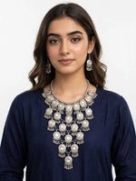 Oxidized silver tiered Y-shaped statement necklace set with mirror accents and matching jhumka dangle earrings — worn with navy blue kurta, South Asian festive jewelry.