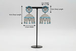 Pair of American diamond earrings with skyblue stone on a stand with measurements indicated.