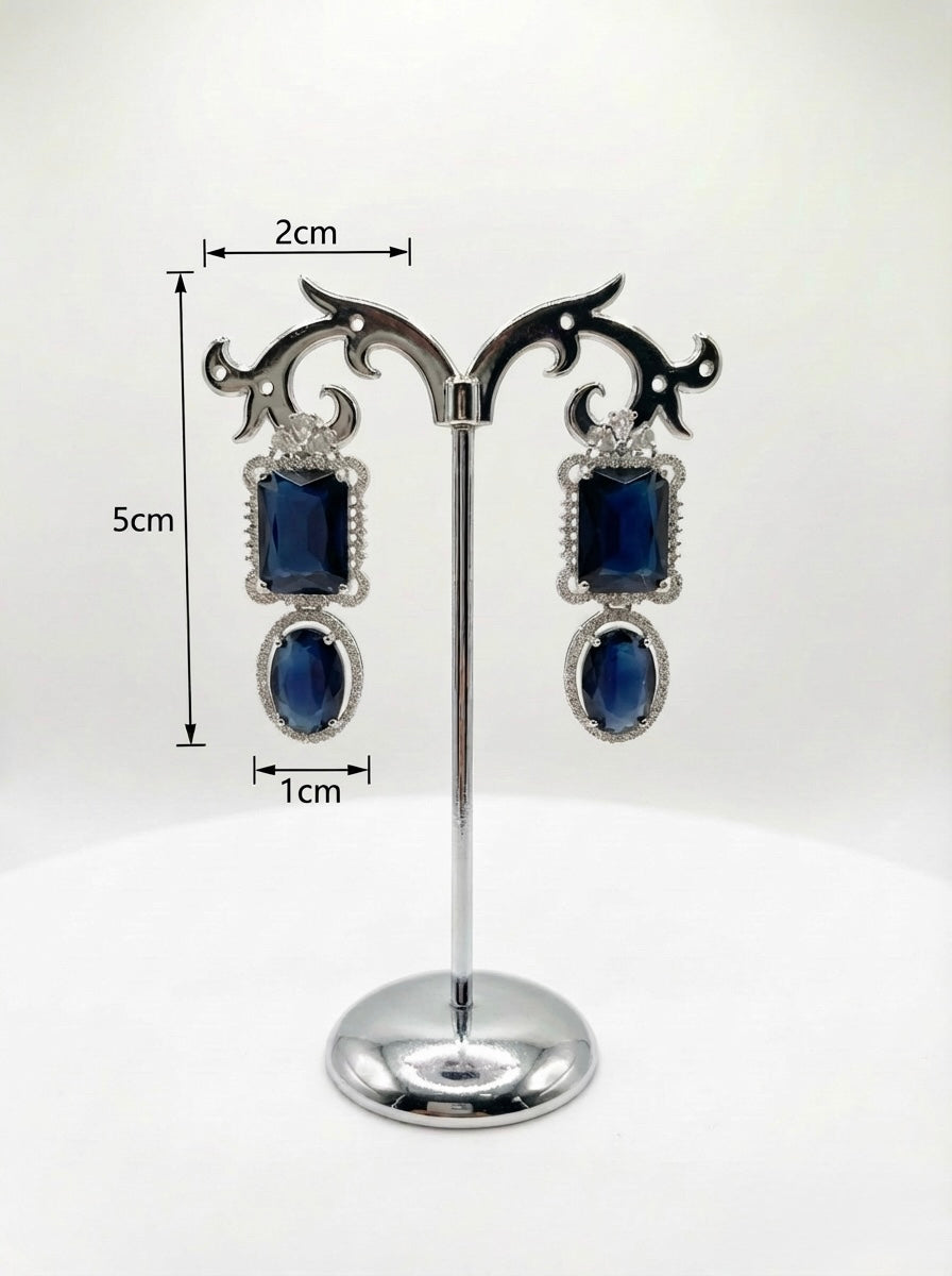 Pair of earrings with blue stones on a stand with measurements