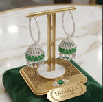 Pair of earrings with green gemstones on a gold stand with 'FAMAZA COUTURE' branding.