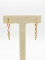 Pair of rose gold hoop earrings featuring a sparkling dangling chain of crystals.
