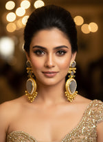 Pair of gold earrings with gemstones on a textured white surface