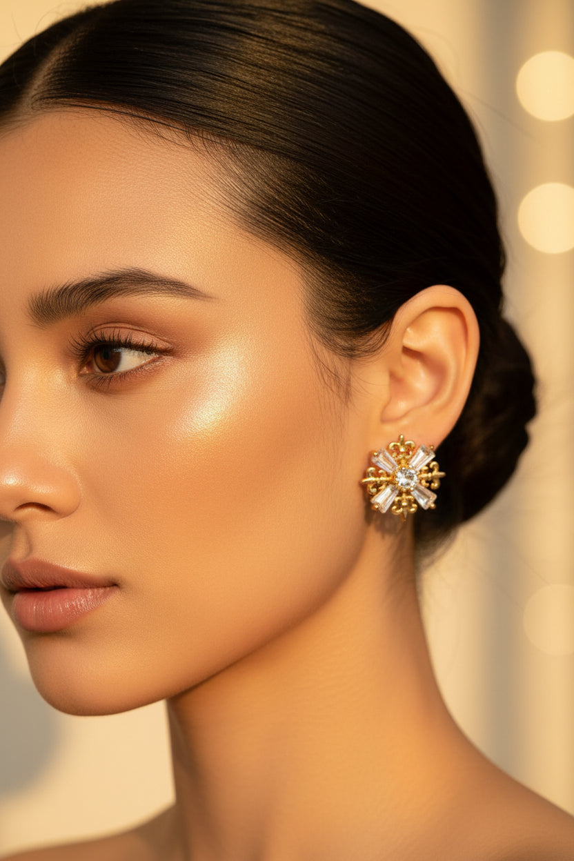 Pair of intricate gold-tone snowflake stud earrings featuring filigree details and sparkling baguette-cut crystals.