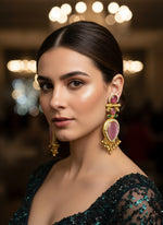 Pair of ornate earrings with pink stones on a beige surface