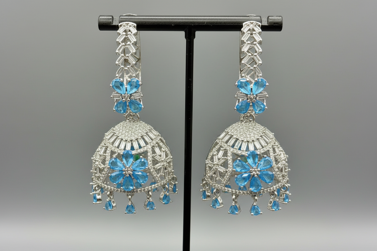 Pair of silver earrings with blue gemstones on a grey background