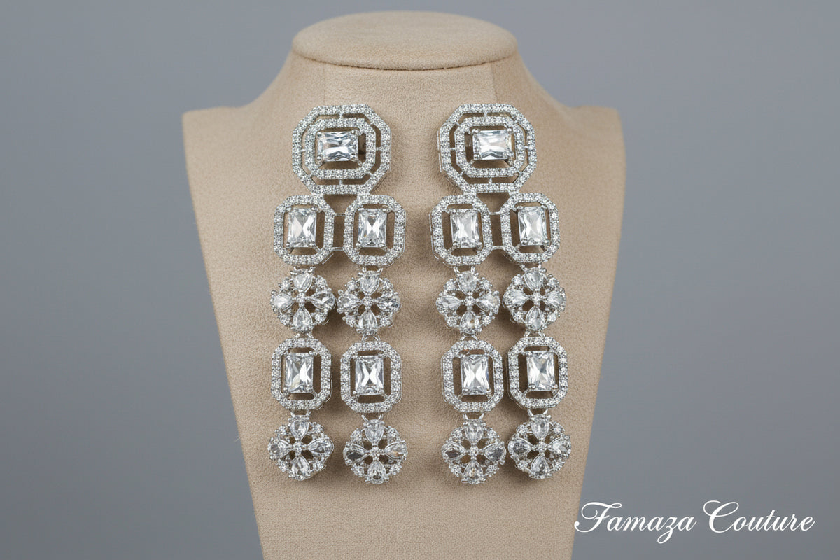 Pair of silver earrings with clear gemstones on a black background