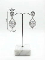 Pair of silver teardrop earrings on a white marble stand with measurements indicated.