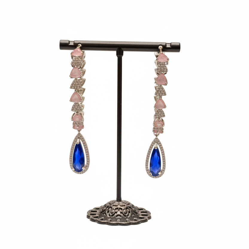 Pair of teardrop-round shaped earrings with blue gemstones on a stand in a jewellery store setting.