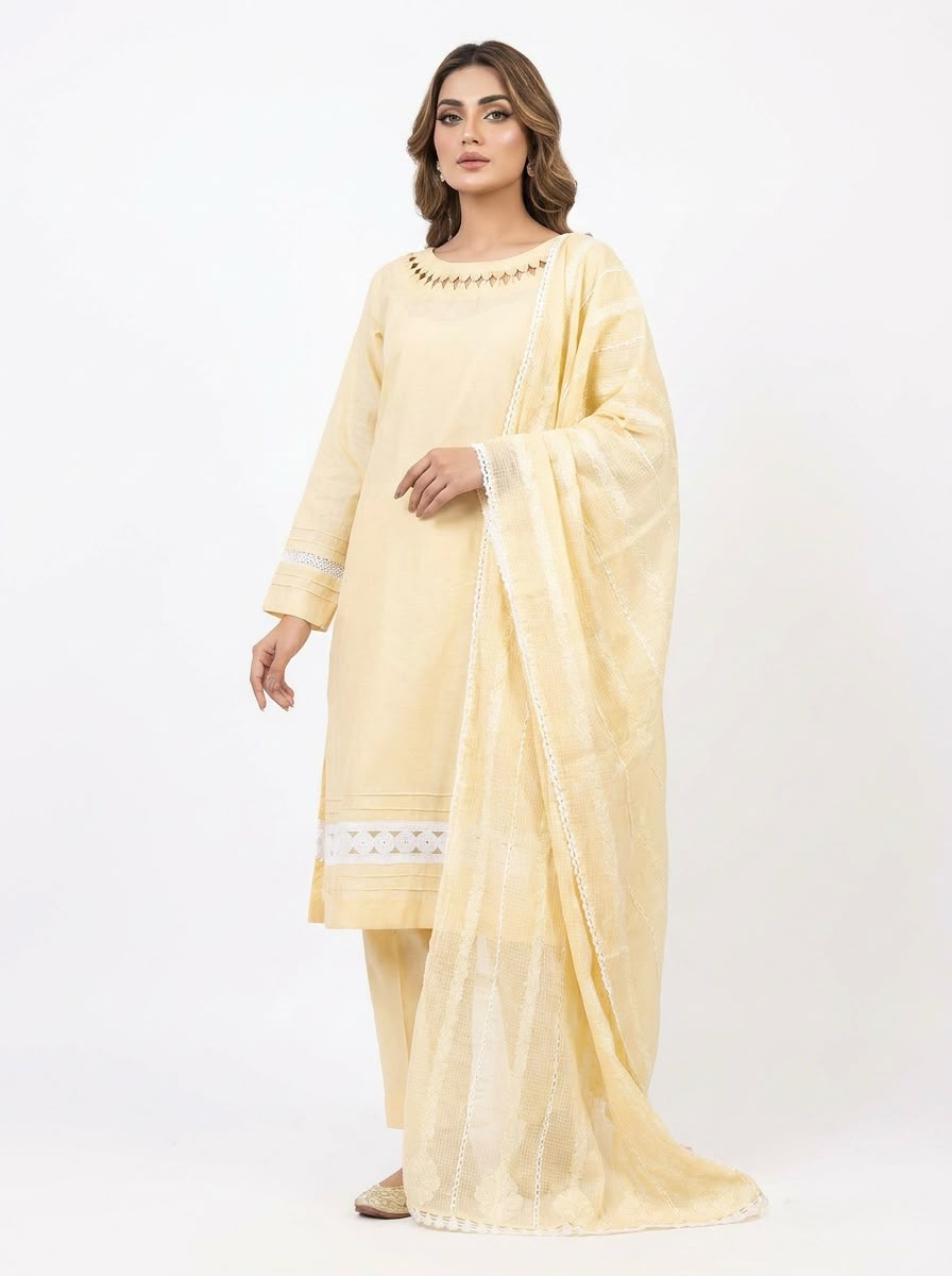 Side-angle view of a model in a pastel yellow cotton salwar kameez suit. Features a matching sheer dupatta with white lace trim, geometric cutout neckline detailing, and a lace insert on the pleated hem.