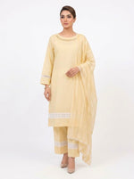 Full-length studio shot of a model wearing a pastel yellow plain cotton three-piece shalwar kameez suit from Famaza Couture. Features a solid pastel yellow kurta with fine neck stitch detailing, matching trousers with intricate white lace inserts and layered pintuck pleats at the hem, and a draped sheer dupatta with white lace borders against a pure white background.