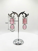Pink earrings on a stand with measurements indicated