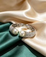 Polished Silver Two-Pearl Pave Crystal Open Cuff Bangle — luxury pearl bracelet on emerald green and cream satin.