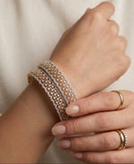High-quality dual-tone American Diamond bangles with an intricate gold lattice and silver stone-set scalloped edges, displayed on a cream-colored cushioned stand.