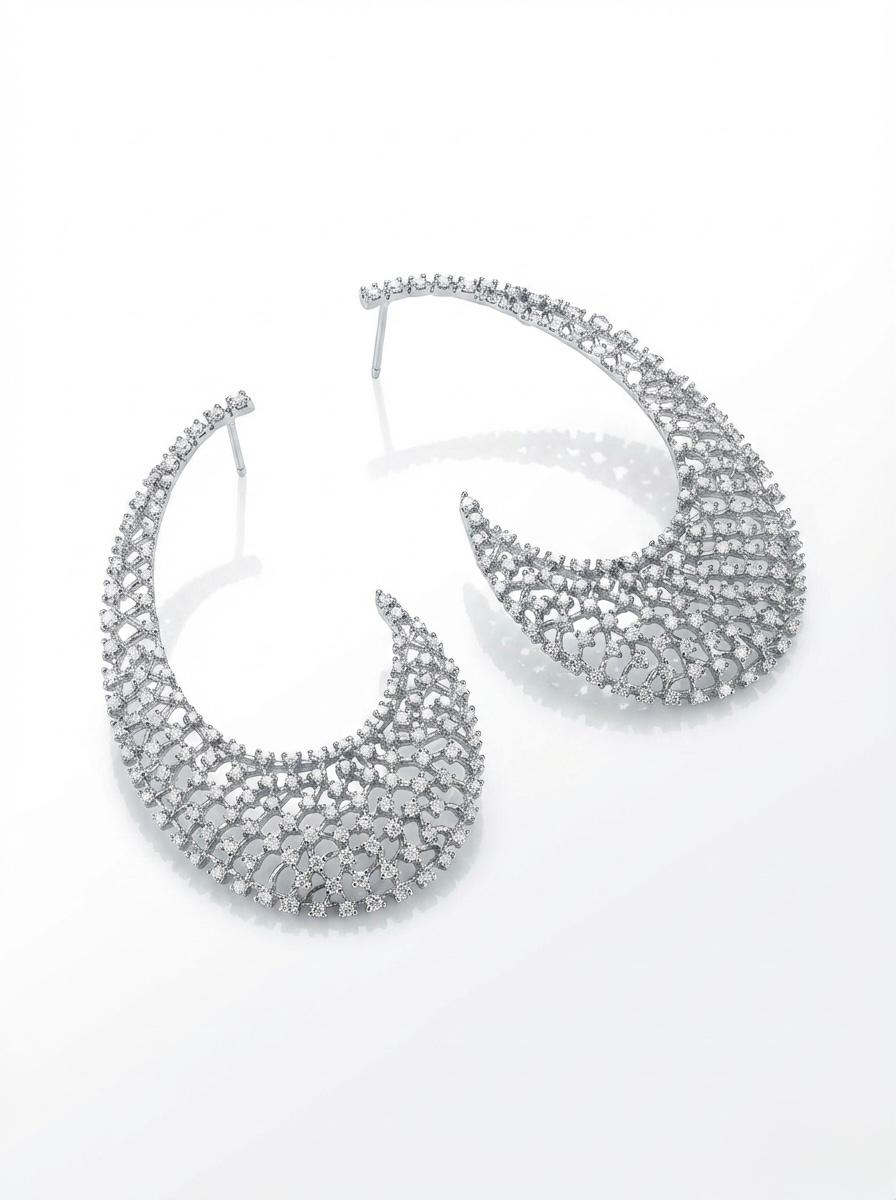 High-angle flat lay photograph of a pair of rhodium-plated statement earrings featuring an intricate floral lattice mesh design encrusted with brilliant White American Diamond (AD) stones on a reflective white surface.