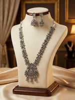 Premium silver oxidised necklace set on a display stand, showcasing the high-grade antique polish and intricate floral detailing for posh jewellery collections.