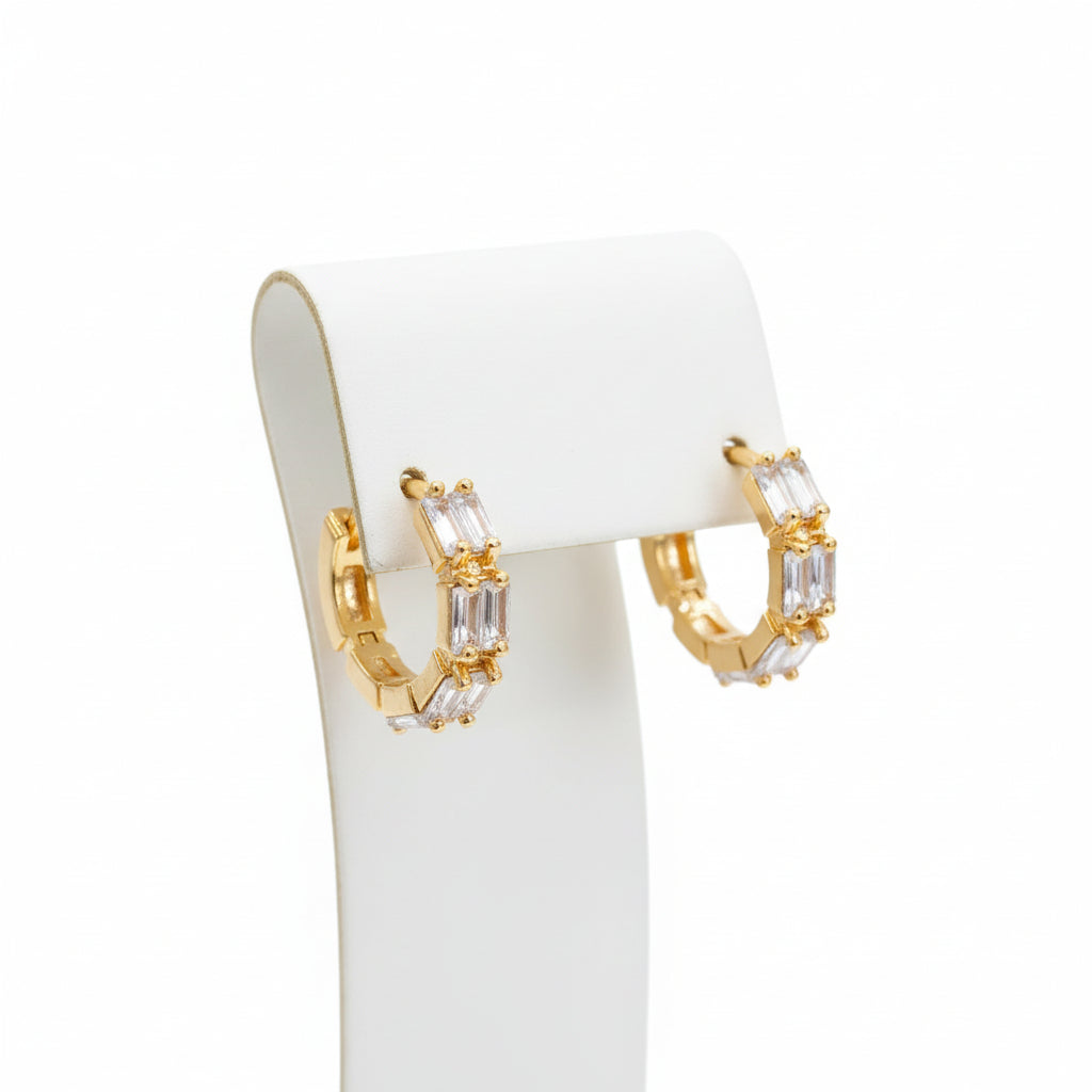 Professional shot of the Luna baguette-cut stone earrings on a display stand, highlighting the high-shine rose gold finish.