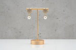 Professional shot of the Serene rose gold polish pearl drop earrings on a display stand, highlighting the brilliant stone clarity.