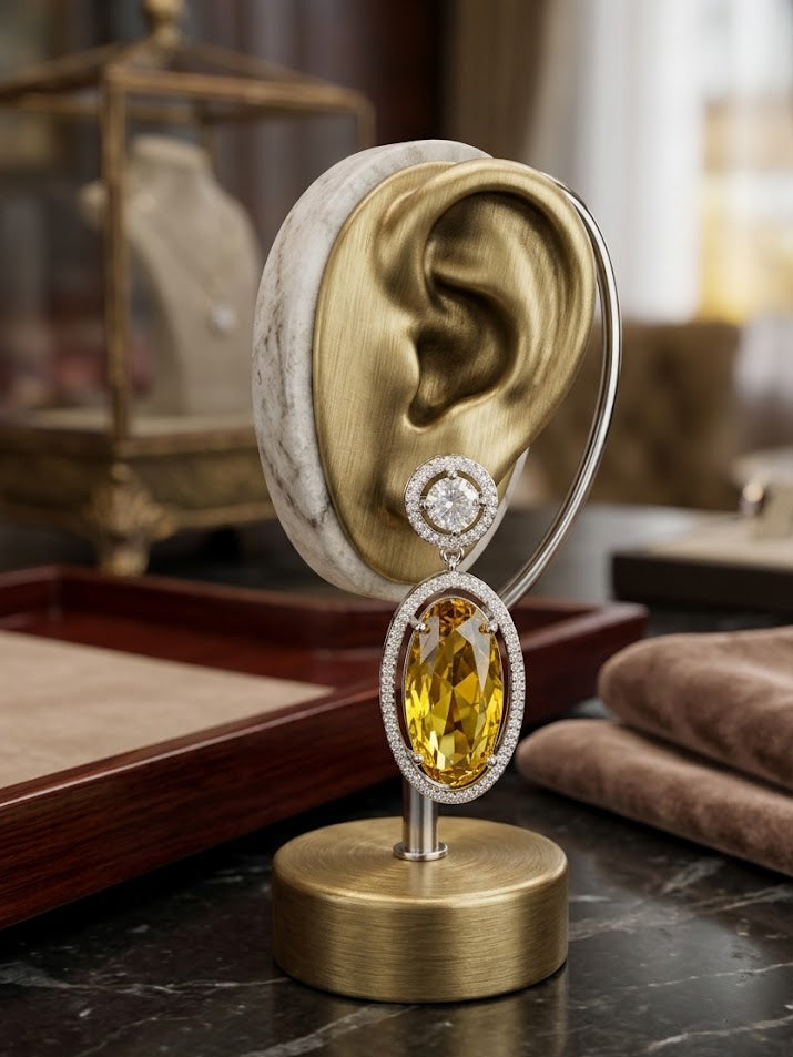 Elegant oval citrine gemstone earring with a diamond halo frame, presented on an ear-shaped stand for size reference.