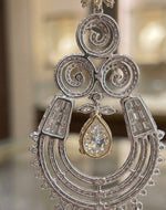 Elegant two-tone chandelier earrings with a pear-cut center stone, ornate filigree design, and high-shine crystal accents, perfect for formal evening wear.