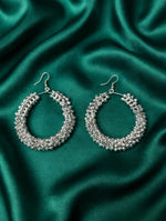 Pair of dense silver-tone crystal teardrop hoop earrings with fishhook closure, displayed on rich emerald green silk satin — Famaza Couture bridal luxury jewelry.