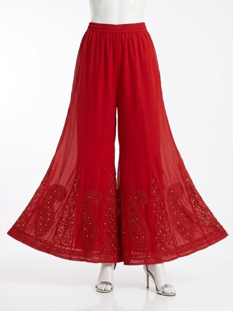 Red georgette gharara with intricate chikankari embroidery and mukaish detailing, wide flared design, displayed on stand.