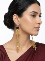 Regal gold laurel leaf drop earrings finished with a deep maroon cushion-cut stone worn by our model.