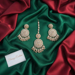 Rose Gold-toned traditional Indian chandelier Maang TIKKA with matching stud earrings, decorated with intricate crystal work, displayed on a black velvet surface with a card labelled Famaza Couture
