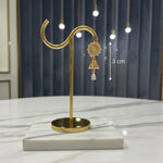 Rose Gold earring stand with a pair of earrings on a marble surface.