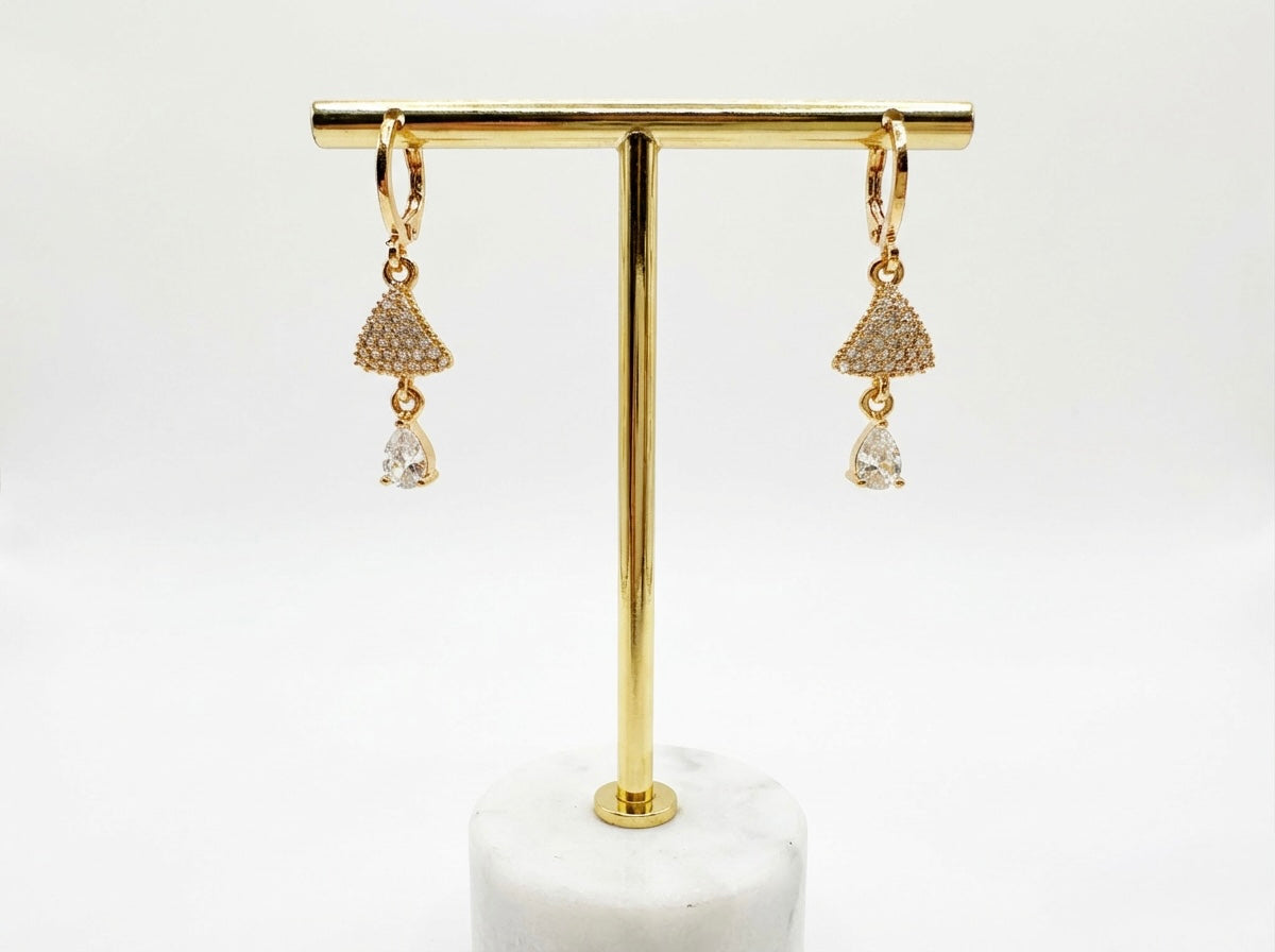 Rose Gold earrings with dangling elements on a gold earring stand against a white background