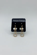 Rose Gold hoop earrings on a black earring card with visible brand name,Famaza Couture placed on a textured white surface.