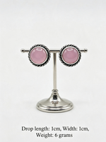 A pair of silver-toned drop earrings with oval pink gemstones, displayed on a silver stand against a white background, with text below showing dimensions and weight.
