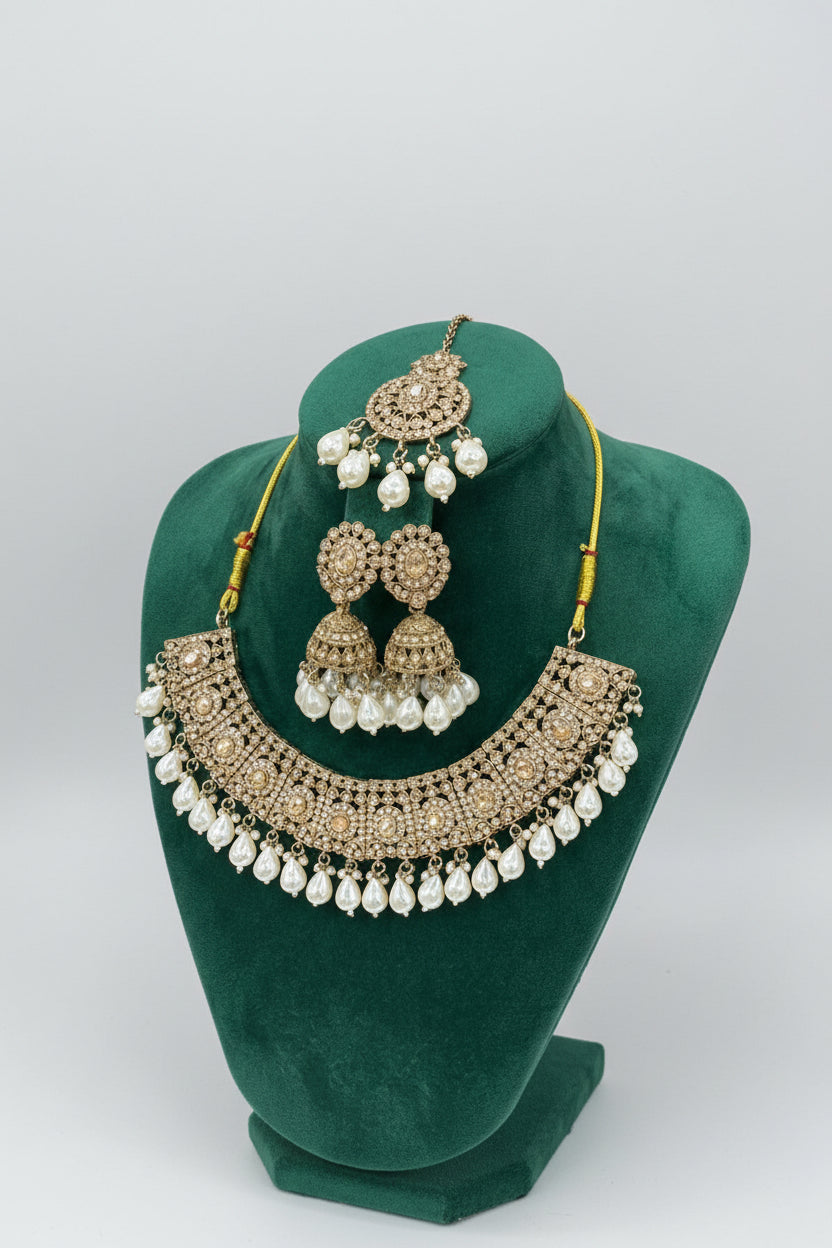 Rose gold choker necklace and 2 jhumkas with maang tikka is displayed on the dummy.