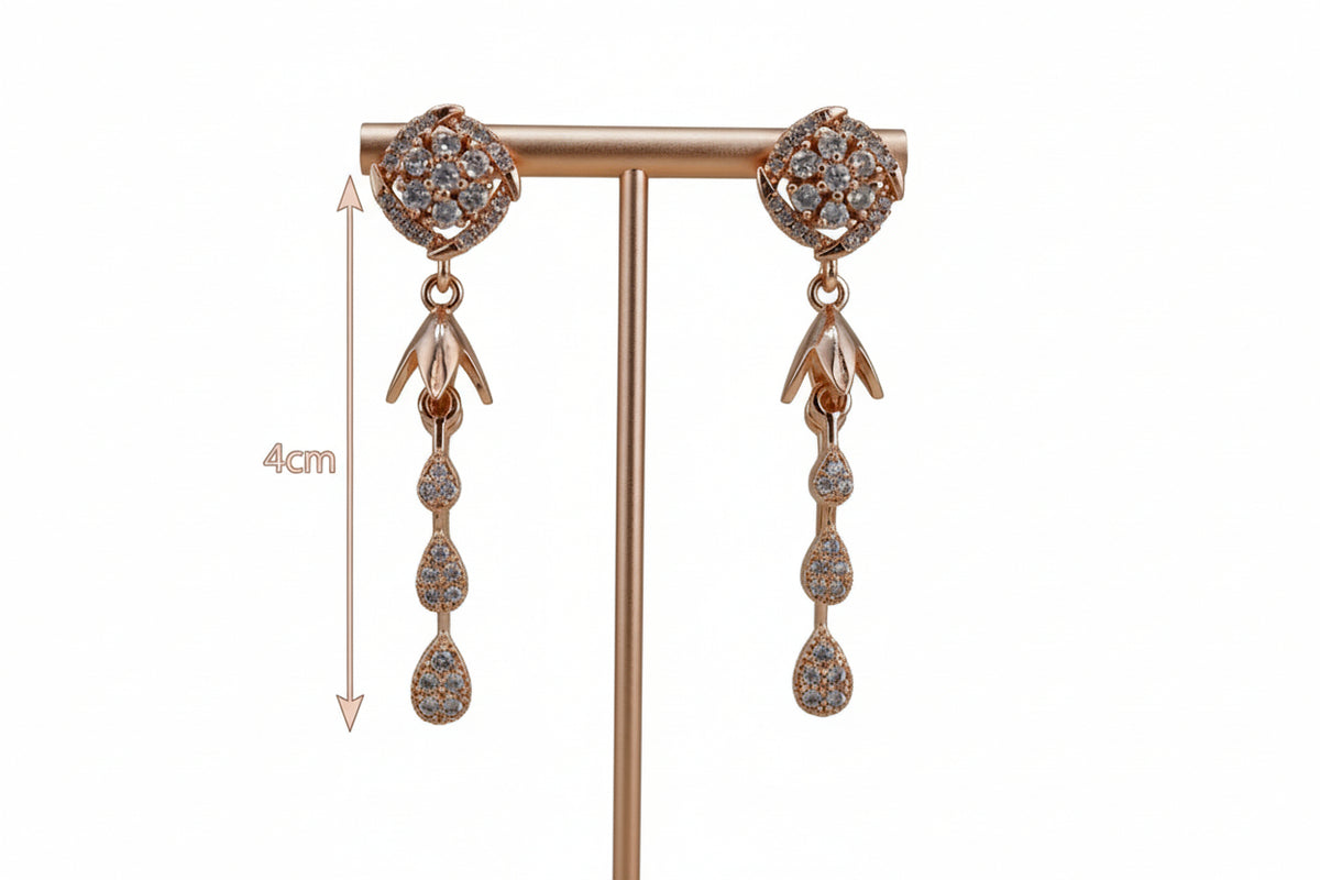 Rose gold earrings with gemstones on a stand against a grey background