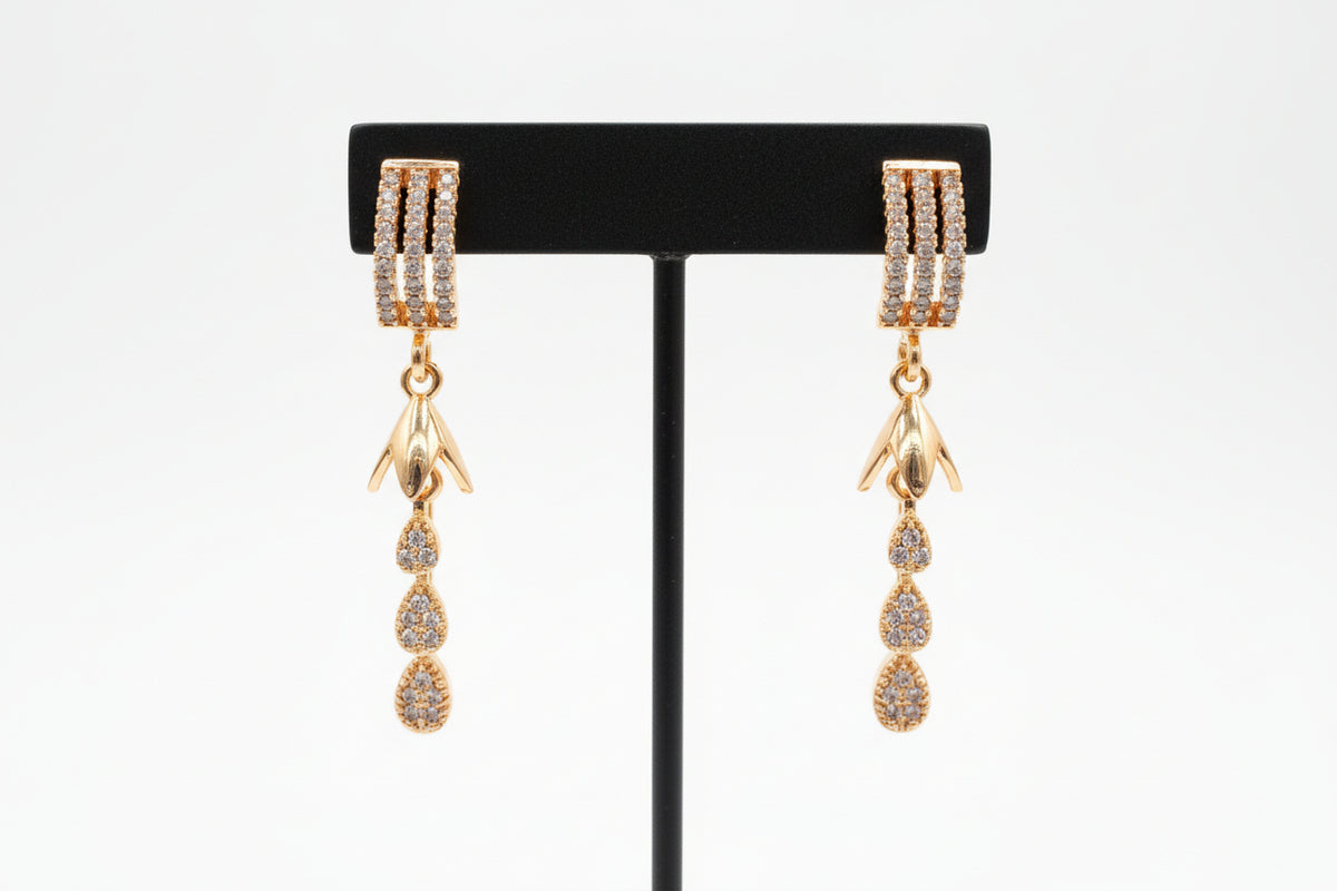 Rose gold polish American Diamond earrings with three rows of white stones on the stud and tiered drop charms.