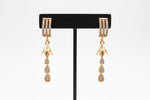 Rose gold polish American Diamond earrings with three rows of white stones on the stud and tiered drop charms.