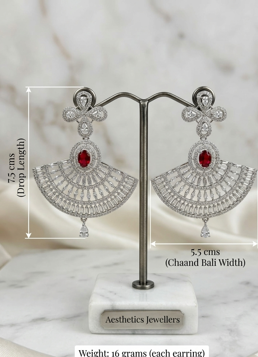 Beautiful model with an elegant low bun showcasing a luxury silver and ruby red American Diamond fan-shaped chandelier earring paired with a classic black off-the-shoulder velvet top.