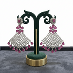 Pair of silver and pink earrings on a green stand with a gray background